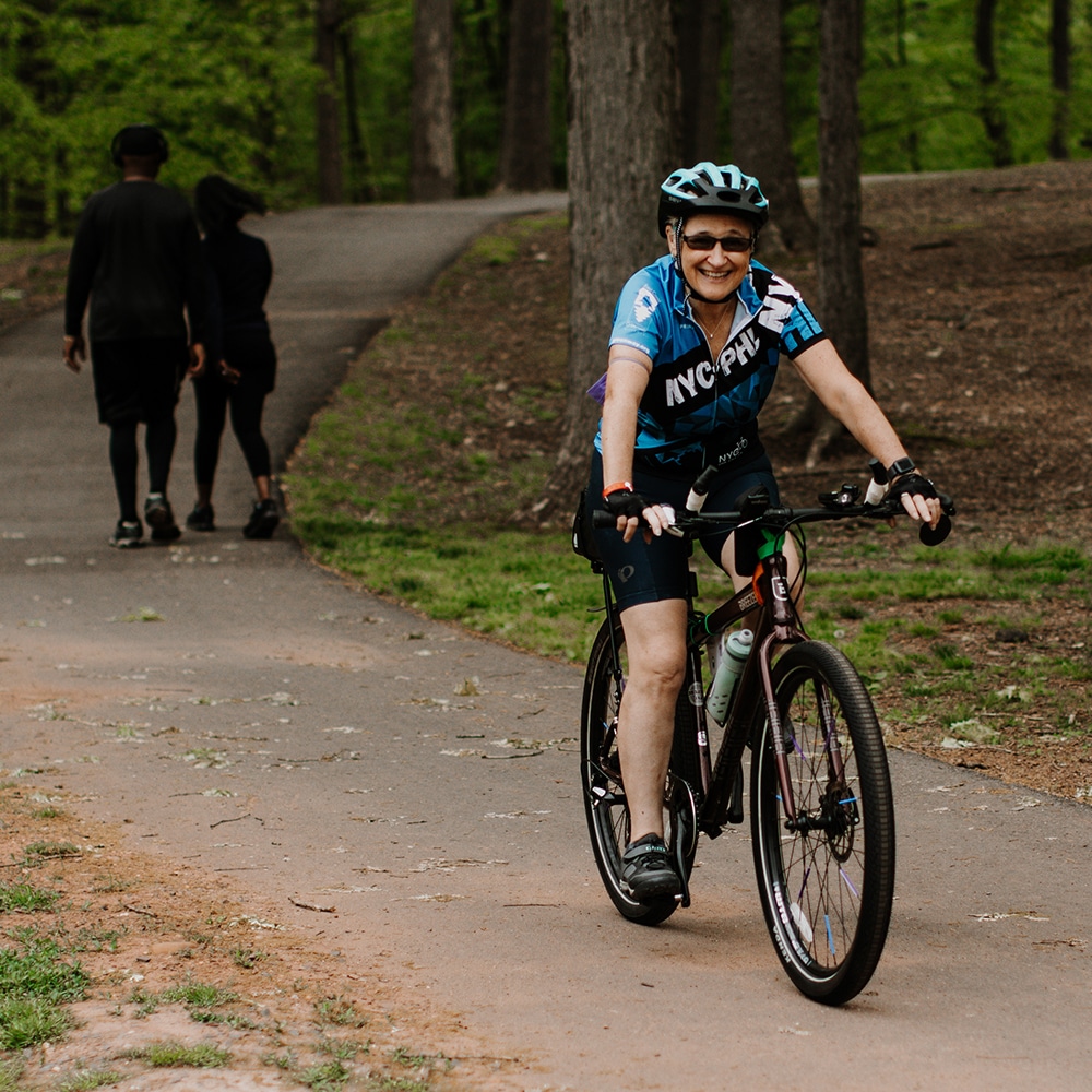 Woman cycling in Roosevelt Park with pedestrians behind