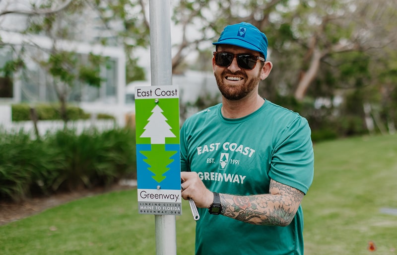 Man standing by a Greenway sign.