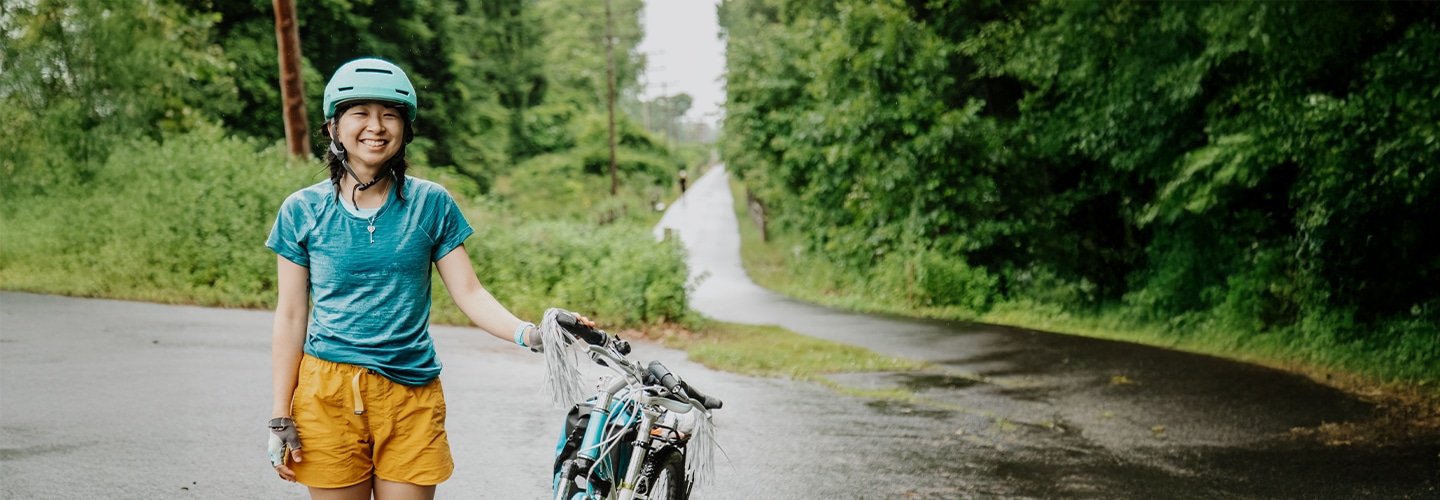 Woman on the Greenway smiling with her bicycle