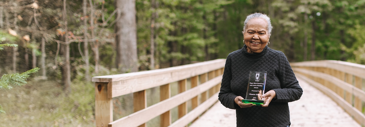 woman holding an award on a trail